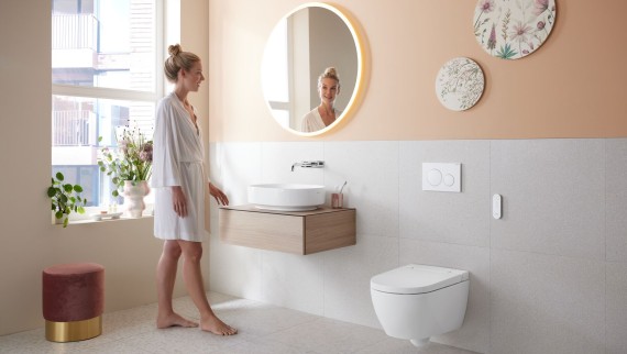 Woman in a bathroom that features a wall-mounted toilet Woman in a bathroom that features a wall-mounted toilet