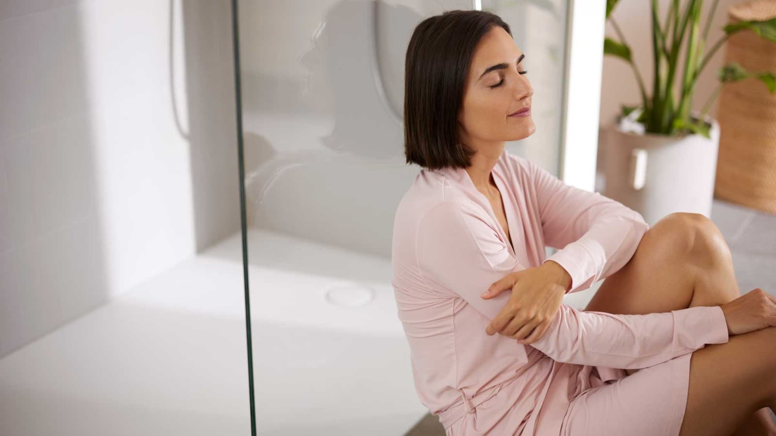 Woman sitting in the bathroom in front of the shower Woman sitting in the bathroom in front of the shower